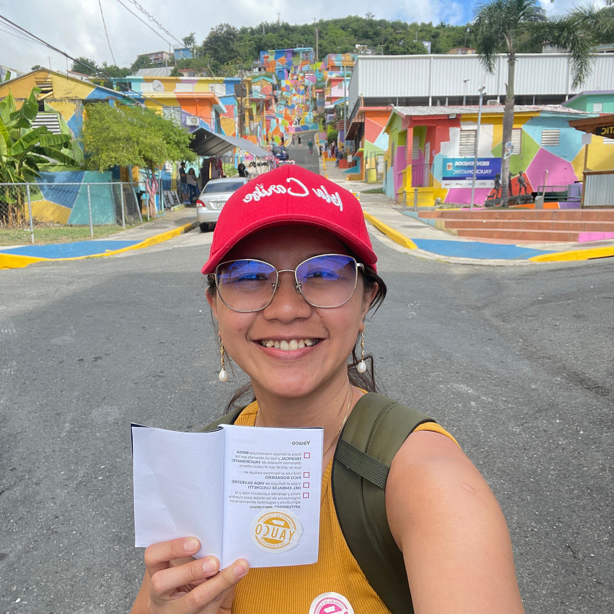 Person holding a document with colorful mural and street in the background
